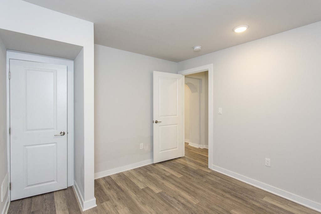 a bedroom with hardwood floors and white walls