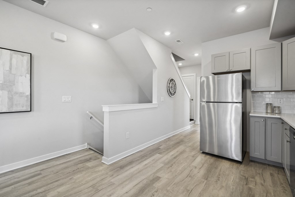 a white kitchen with a stainless steel refrigerator and white cabinets