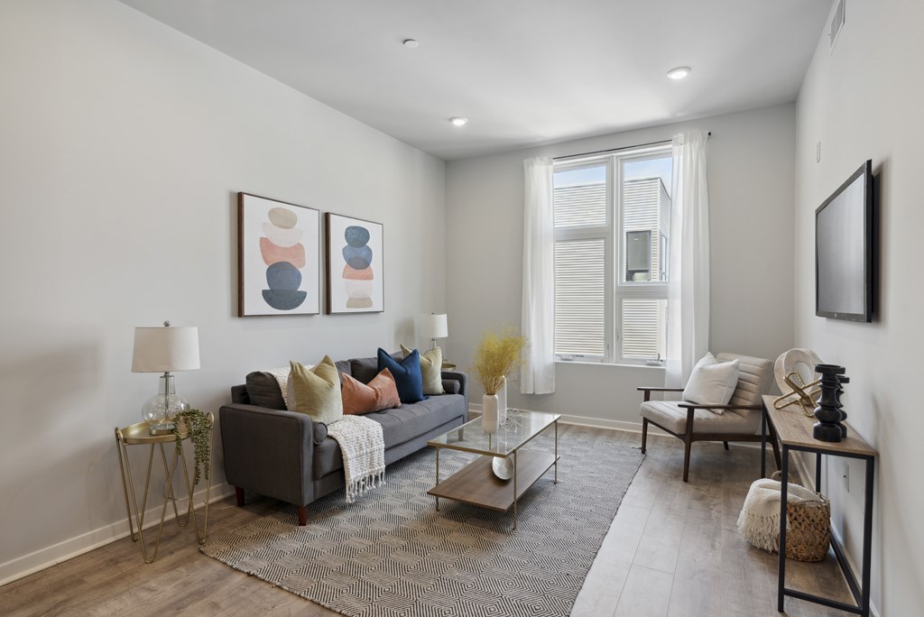 A living room with a grey couch, a coffee table, and a large window.