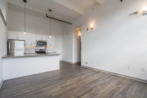 an empty living room and kitchen with a counter top and a refrigerator