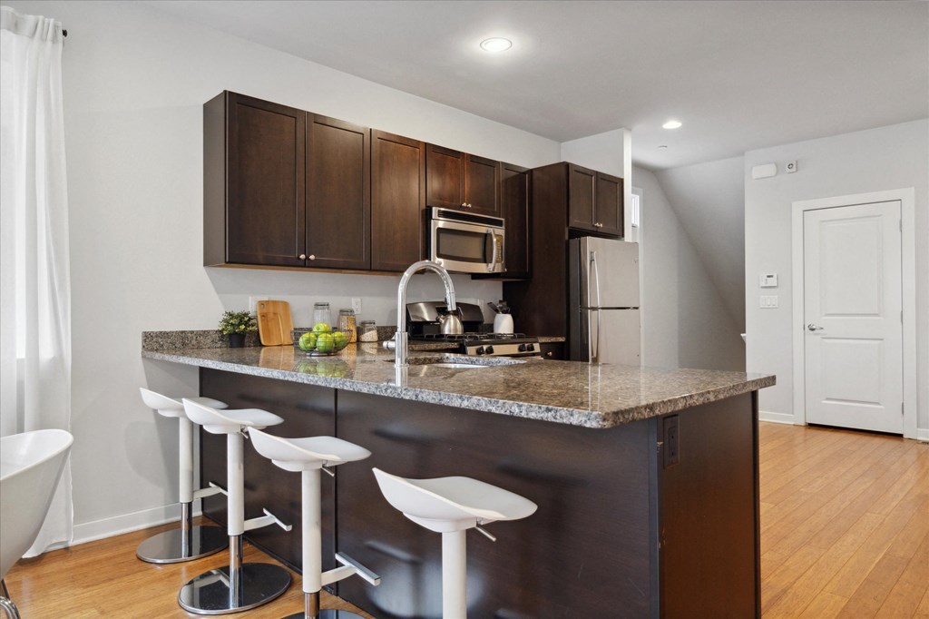 a kitchen with a granite counter top and dark wood cabinets