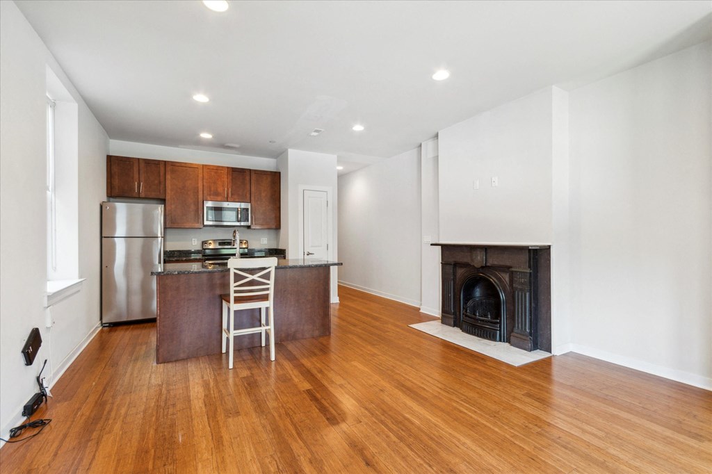 a living room with a fireplace and a kitchen with wooden floors