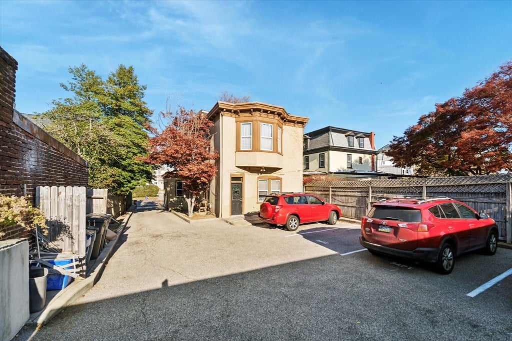 the front of a house with a parking lot and two red cars
