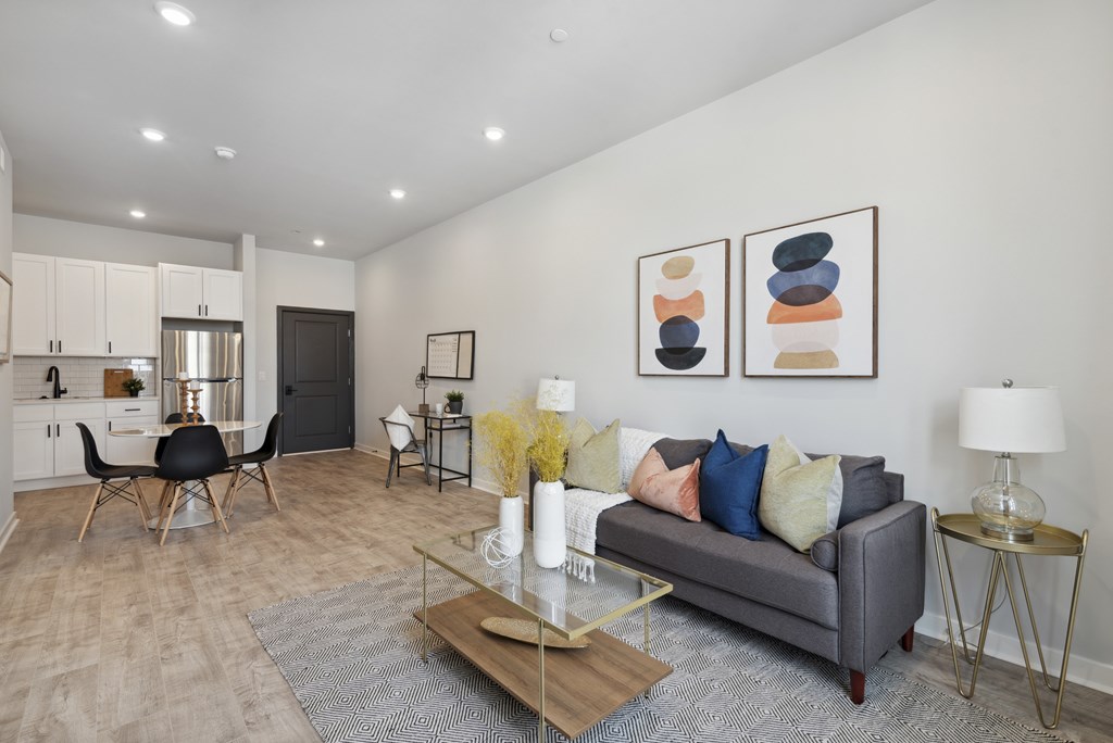 A modern living room with a grey couch, a wooden coffee table, and a glass table lamp.