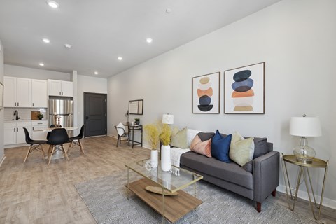 A modern living room with a grey couch, a wooden coffee table, and a glass table lamp.