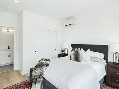 A bedroom with a large bed and a white wall.