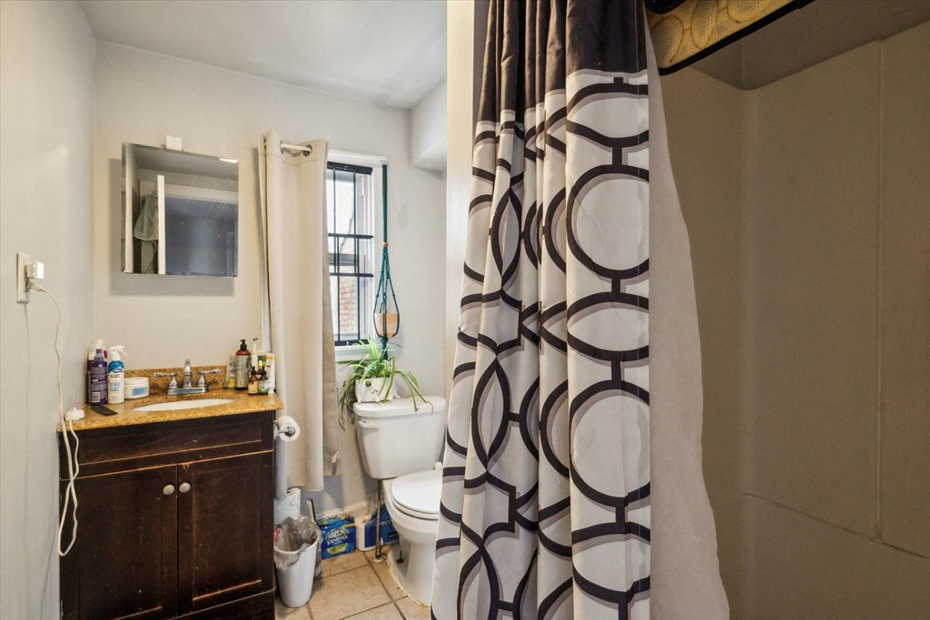 a bathroom with a shower curtain and a toilet and a sink