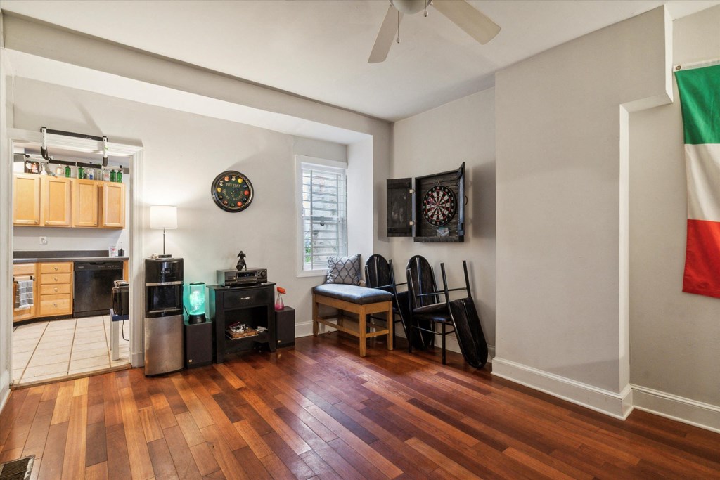 a living room with a hard wood floor and a kitchen with a table and chairs