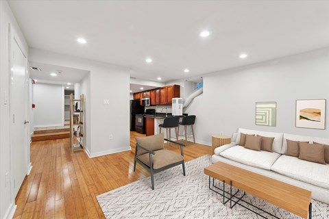 a living room with a couch and a table and a kitchen in the background