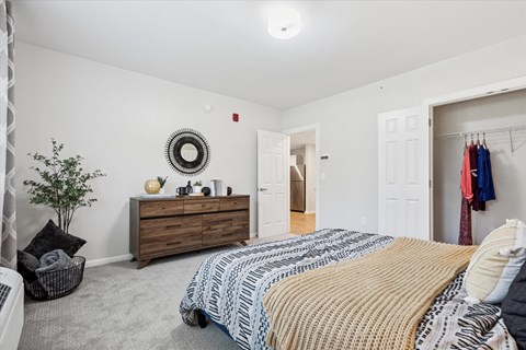 A bedroom with a bed, dresser, and a mirror on the wall.