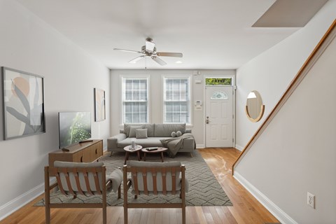 a living room with a couch and chairs and a ceiling fan