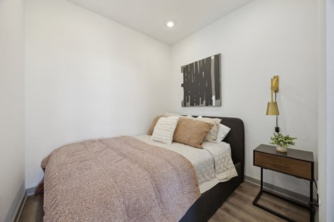 a bedroom with white walls and a bed with a blanket and pillows at The Commons On Ludlow Apartments, Philadelphia, Pennsylvania