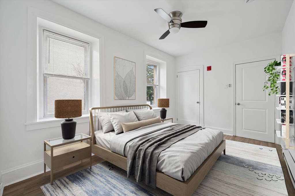 A bedroom with a bed, nightstand, and a ceiling fan.