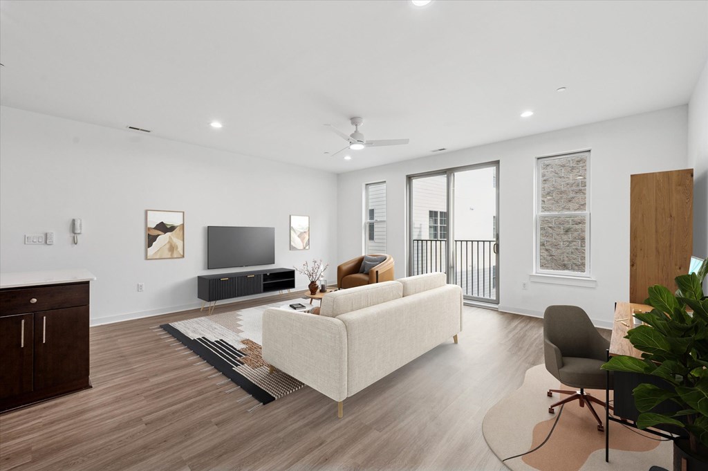 A living room with a white couch, a television, and a ceiling fan.