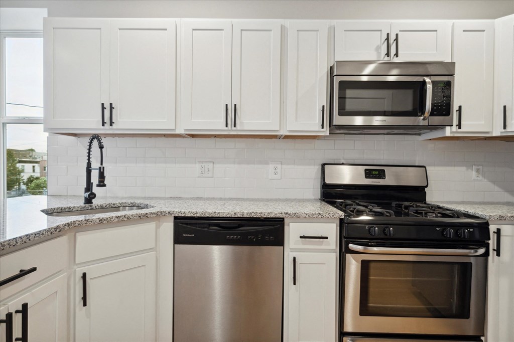a white kitchen with stainless steel appliances and white cabinets