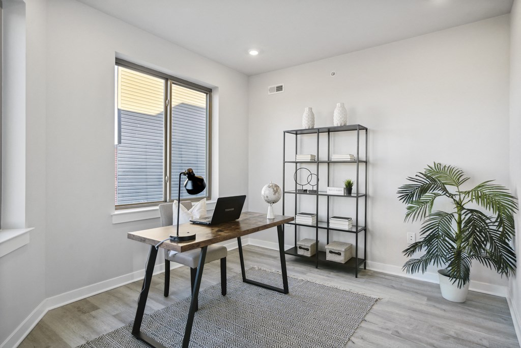 an office with a large window and a desk with a laptop