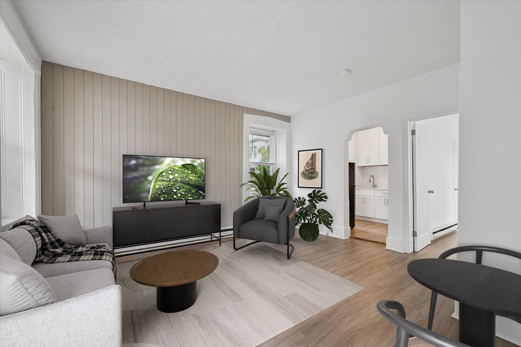 A living room with a grey sofa, a black chair, a wooden coffee table, and a TV on a cabinet.