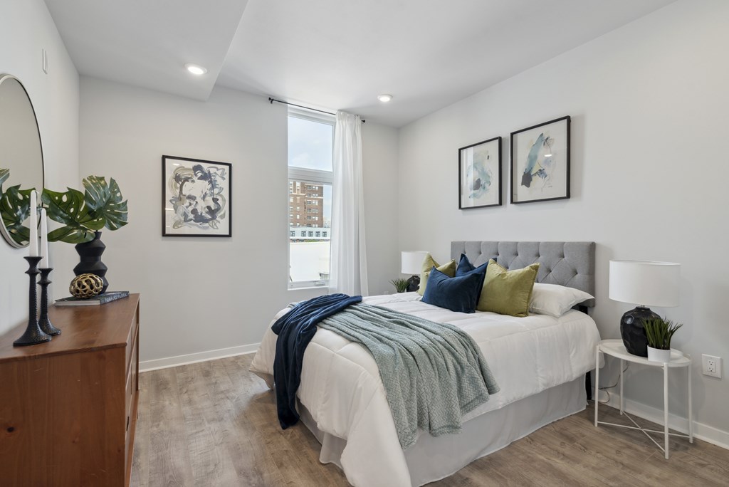 A bedroom with a bed, nightstand, and a mirror.