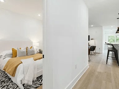 A bedroom with a bed covered in a white and gold comforter.