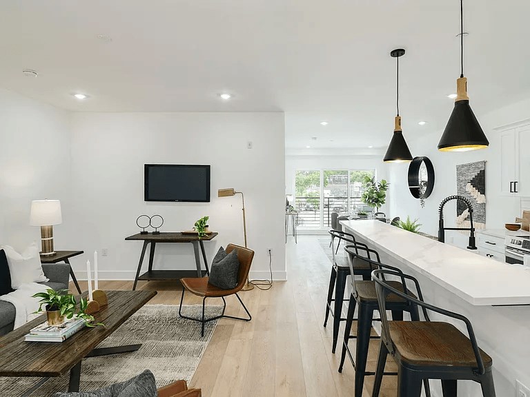 A modern living room with a long white table and black chairs.