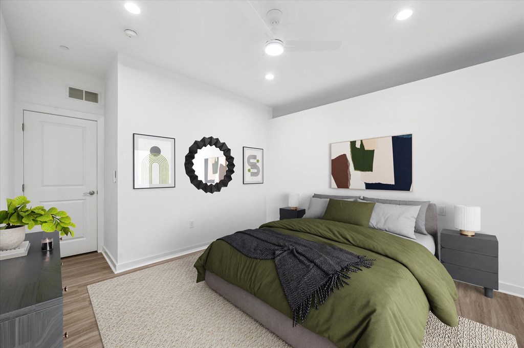 A bedroom with a bed, a plant, and pictures on the wall.