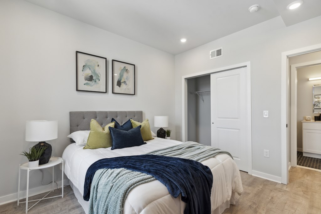 A bedroom with a bed, two lamps, a nightstand, and two pictures on the wall.