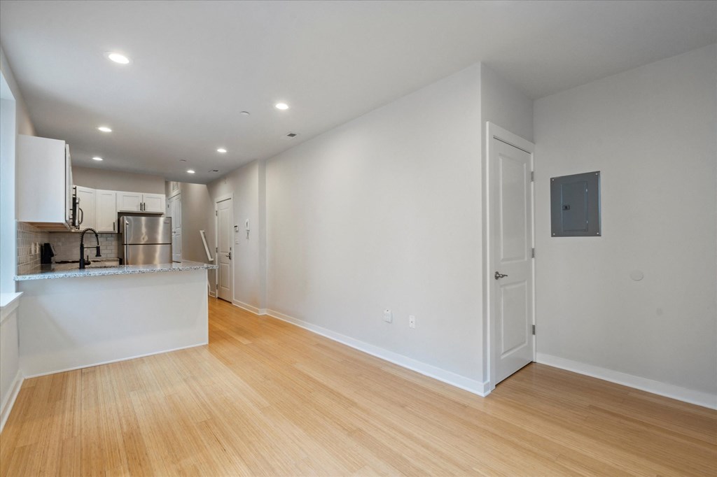 a living room and kitchen with wood floors and white walls