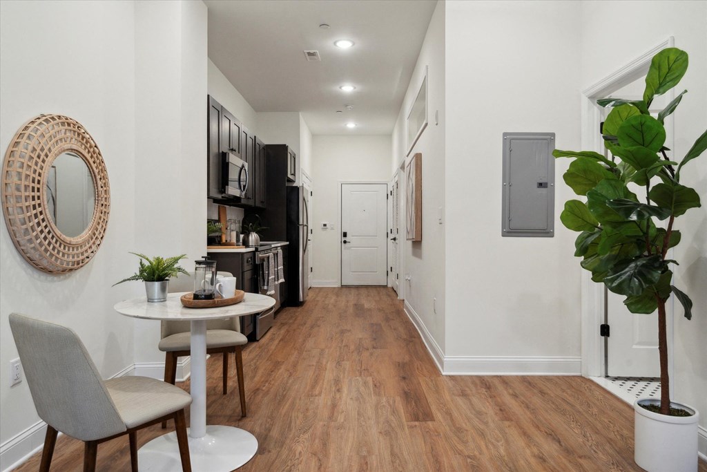 a living room with a table and chairs and a hallway with a door to a