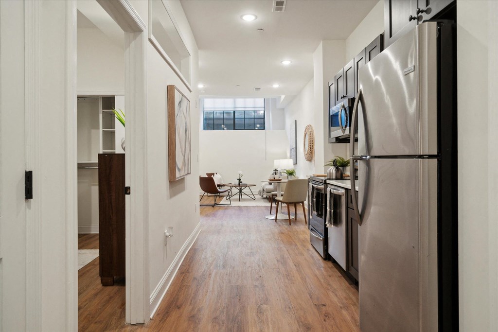 a kitchen and living room with stainless steel appliances and white walls