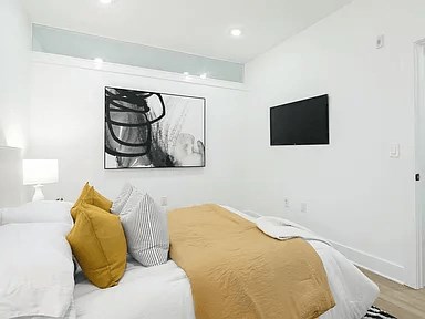 A bedroom with a bed covered in a white and yellow comforter.