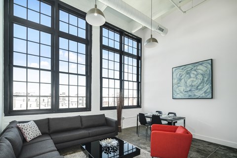 A living room with a black couch, a red chair, and a painting on the wall.