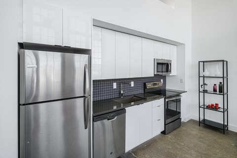 A modern kitchen with a stainless steel refrigerator and white cabinets.