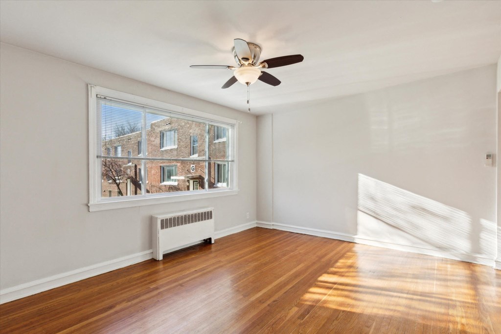 an empty living room with a large window and a ceiling fan