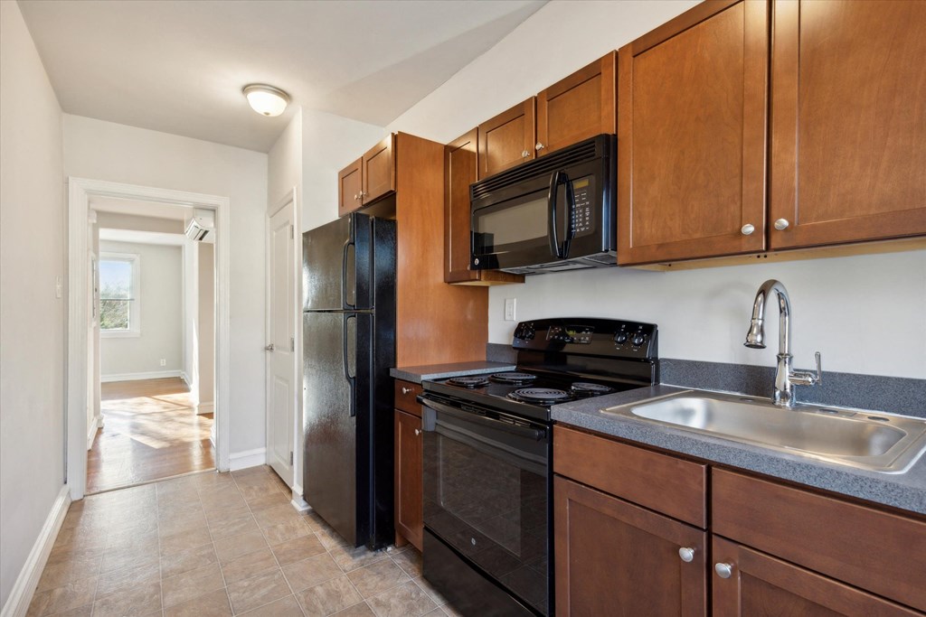 a kitchen with black appliances and wooden cabinets and a sink
