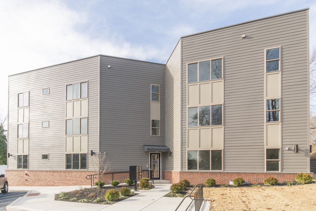 the front of a gray building with a sidewalk in front of it