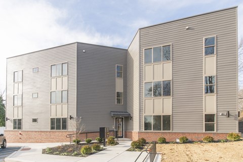 the front of a gray building with a sidewalk in front of it