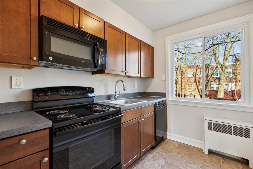 a kitchen with black appliances and wooden cabinets and a window