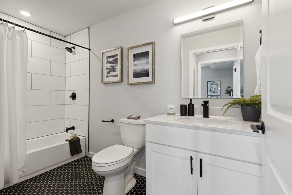 A white bathroom with a toilet, sink, and shower.