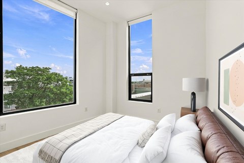 A bedroom with a large bed and a view of the city through the window.