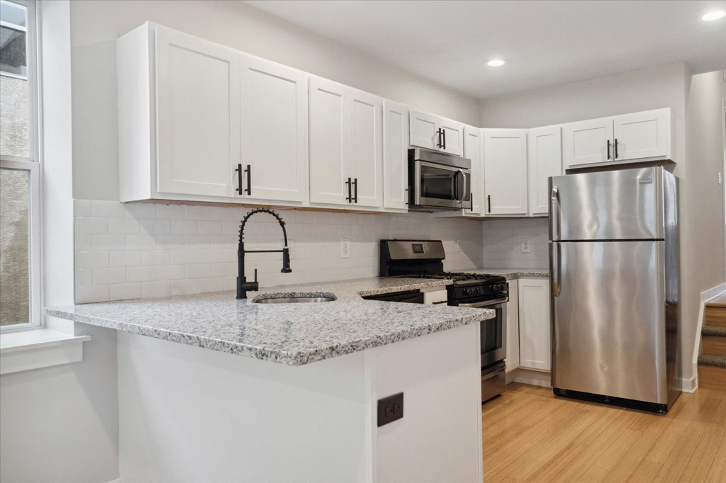 a kitchen with white cabinets and a counter top and a stainless steel refrigerator