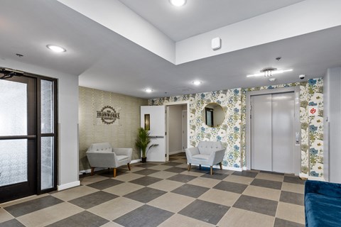 a lobby with a checkered floor and two chairs and a door