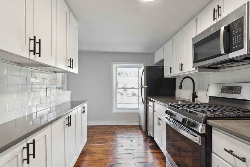 a kitchen with white cabinets and black appliances