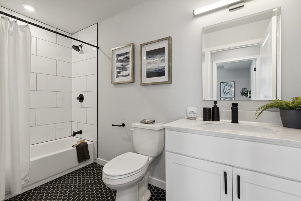 A white bathroom with a black and white tiled floor.