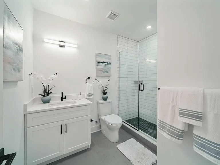 A white bathroom with a glass shower stall and a towel rack.