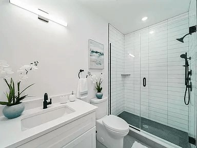 A white bathroom with a glass shower stall and a white toilet.