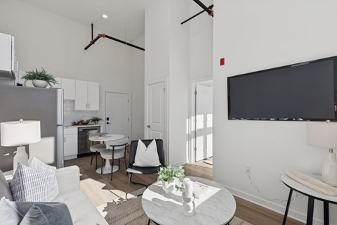 A modern living room with a grey sofa, a white coffee table, and a black television mounted on the wall.