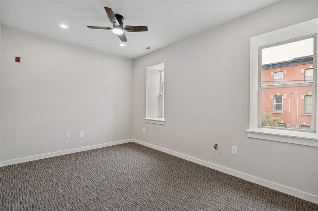 an empty living room with a ceiling fan and a window