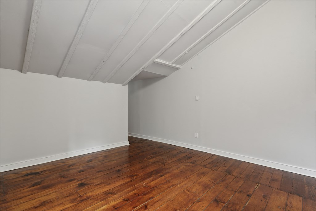 an empty room with a wooden floor and grey walls