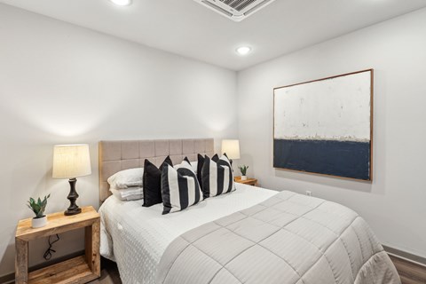 A bedroom with a large bed and a painting on the wall.