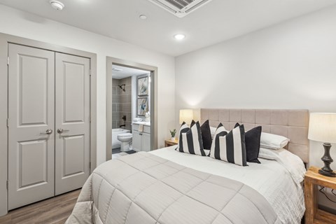 A bedroom with a large bed and a bathroom visible through the door.